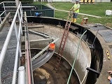 Worker inspecting large open industrial tank.