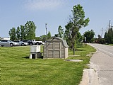 Suburban landscape with electrical boxes and green grass.