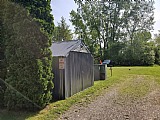 Rural setting with shed and mailbox near trees.