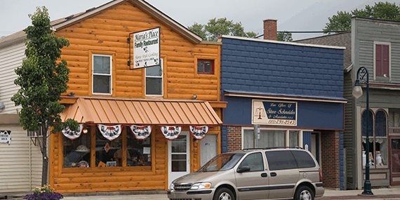 Small town street with wooden building and parked car.